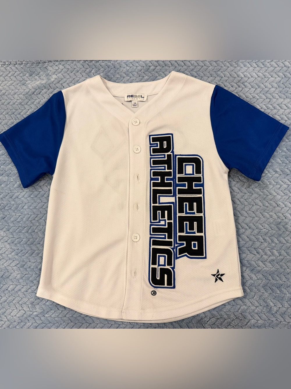 rebels White Jersey with Blue Sleeves and 'Cheer Athletics' Graphic